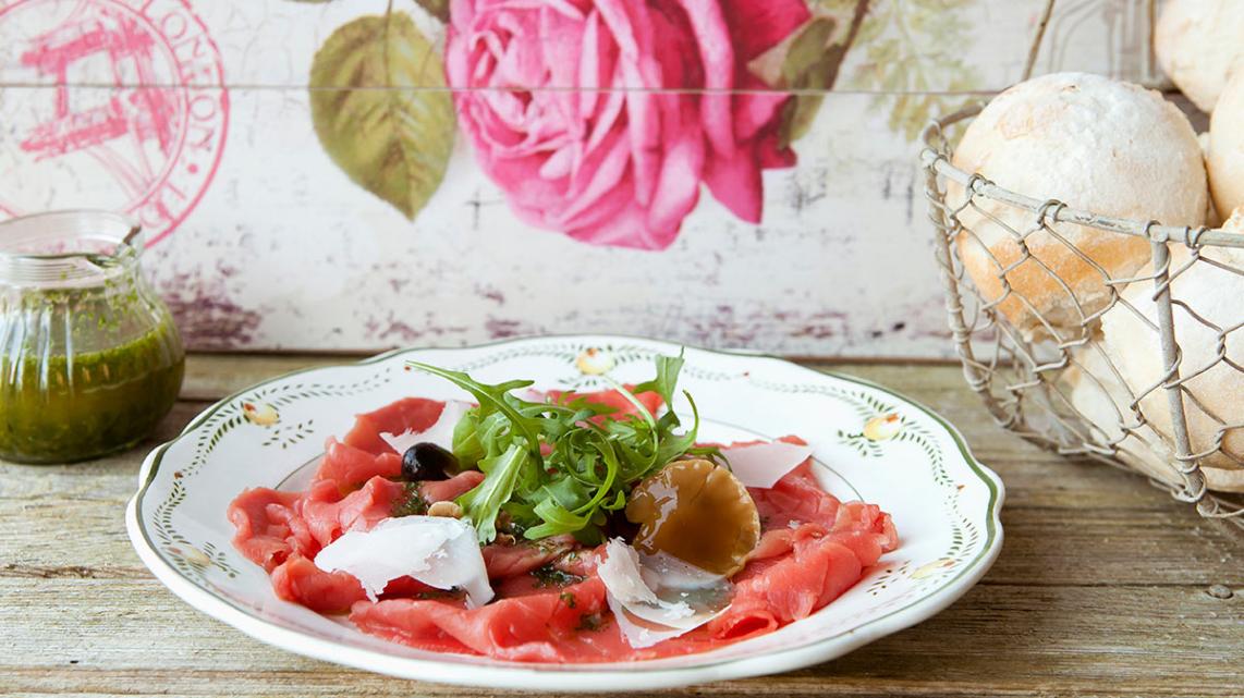 Rundscarpaccio met basilicumolie, parmezaanse kaas, paddenstoelen op olie en notensla