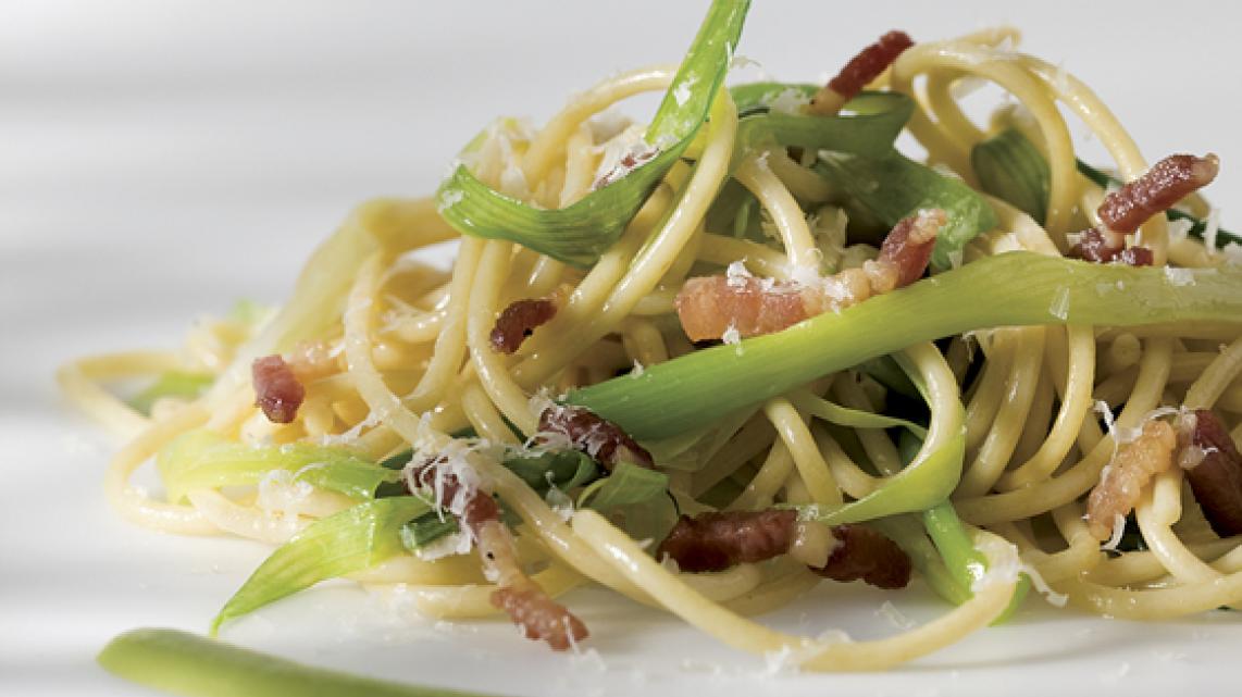 Volkorenpasta met bosui, krokante spekjes, erwtensausje en parmesaan