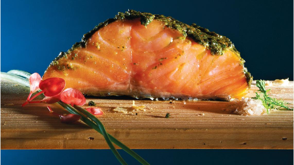 Zalmfilet op een plank gegrild met zelfgemaakte kruidenpesto